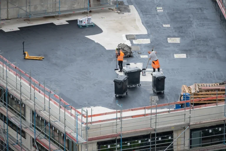 Two workers installing or maintaining commercial flat roofing system on industrial building