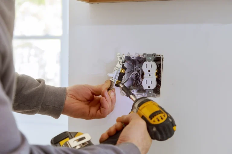 Electrician installing or maintaining electrical outlet with tools and wiring visible