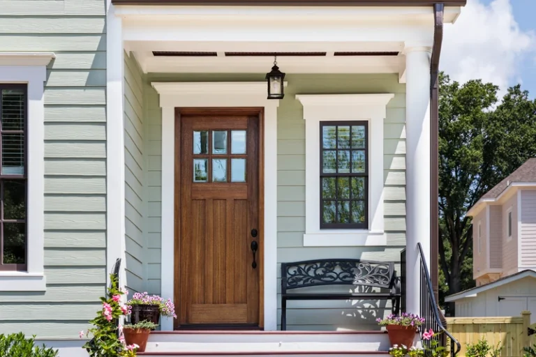 Residential home entrance with wooden door, transom window, and white trim framing