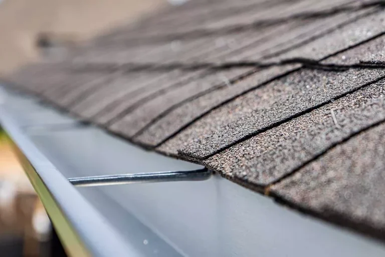 Residential gutter guard installed on home roof edge with shingles visible