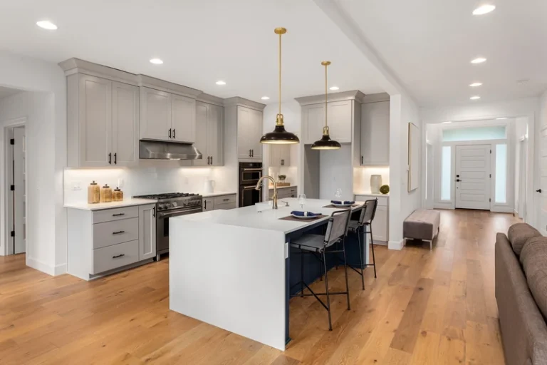 Modern kitchen with white cabinetry, island, stainless steel appliances, and wood flooring